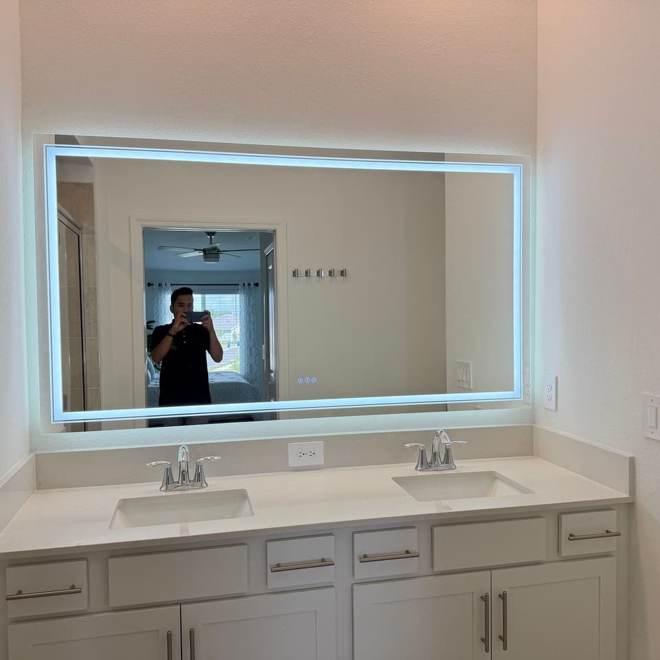 Mueble de baño con espejo LED retroiluminado montado sobre doble lavabo y gabinetes blancos tipo shaker